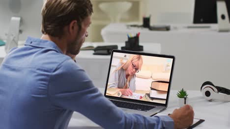 Profesor-Caucásico-Usando-Una-Computadora-Portátil-En-Una-Videollamada-Con-Una-Estudiante,-Tomando-Notas