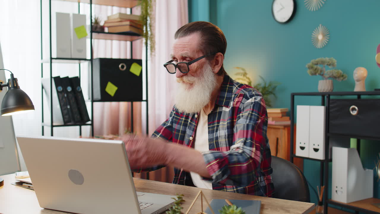 Senior man freelancer taking break from work wearing 3d glasses eating popcorn watching movie film