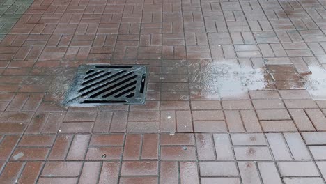 Rain-drops-falling-on-drain-opening-in-Hong-Kong,-China