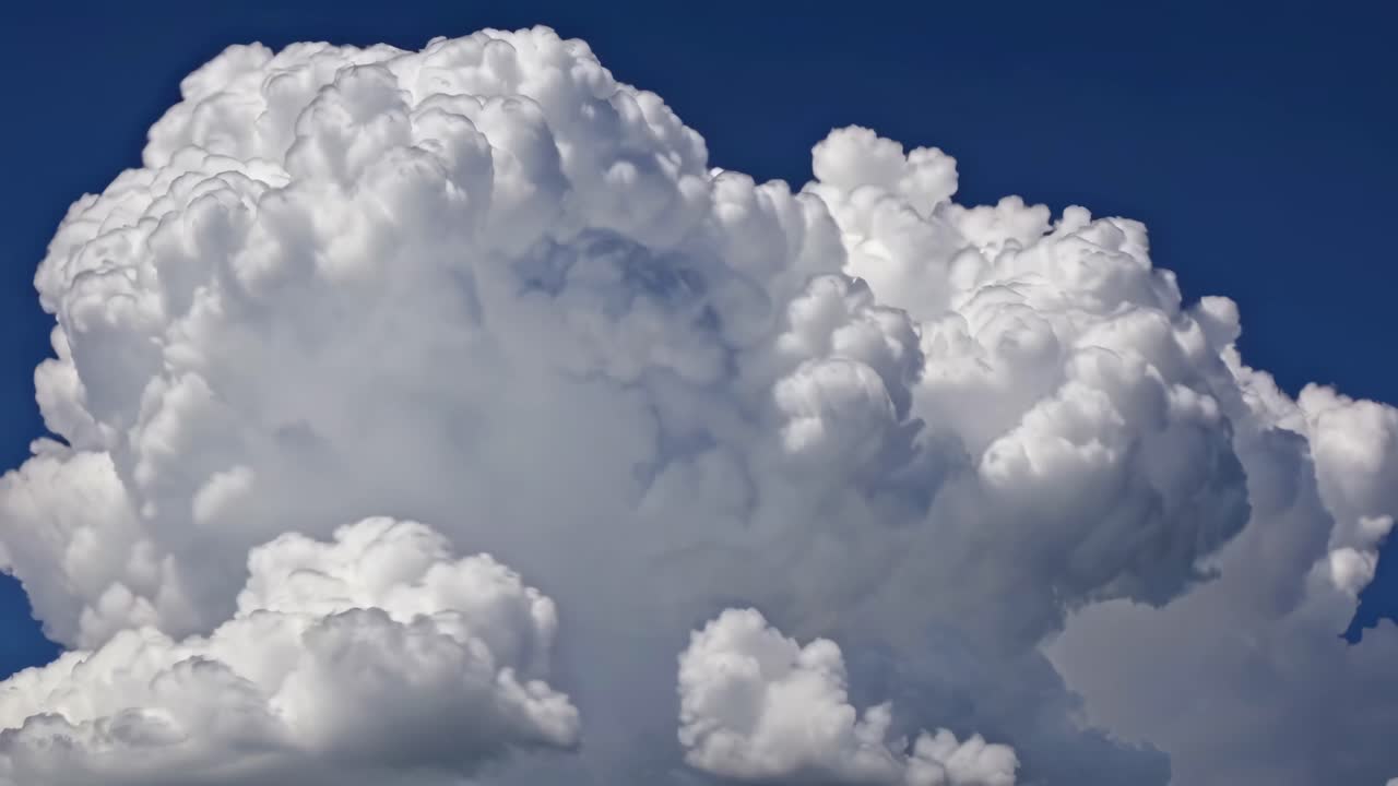 A video captures towering cumulus clouds from a low-angle perspective, emphasizing their fluffy