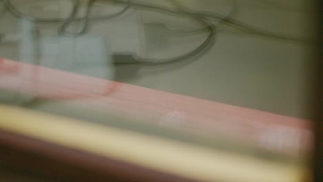 Slow-Motion-Raindrops-Falling-on-Window-Sill-with-Plug-Charger-Reflection