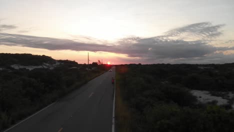aerial shot along the road: driving a motocycle and sunset