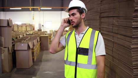 Warehouse-worker-talking-on-the-phone-looking-around