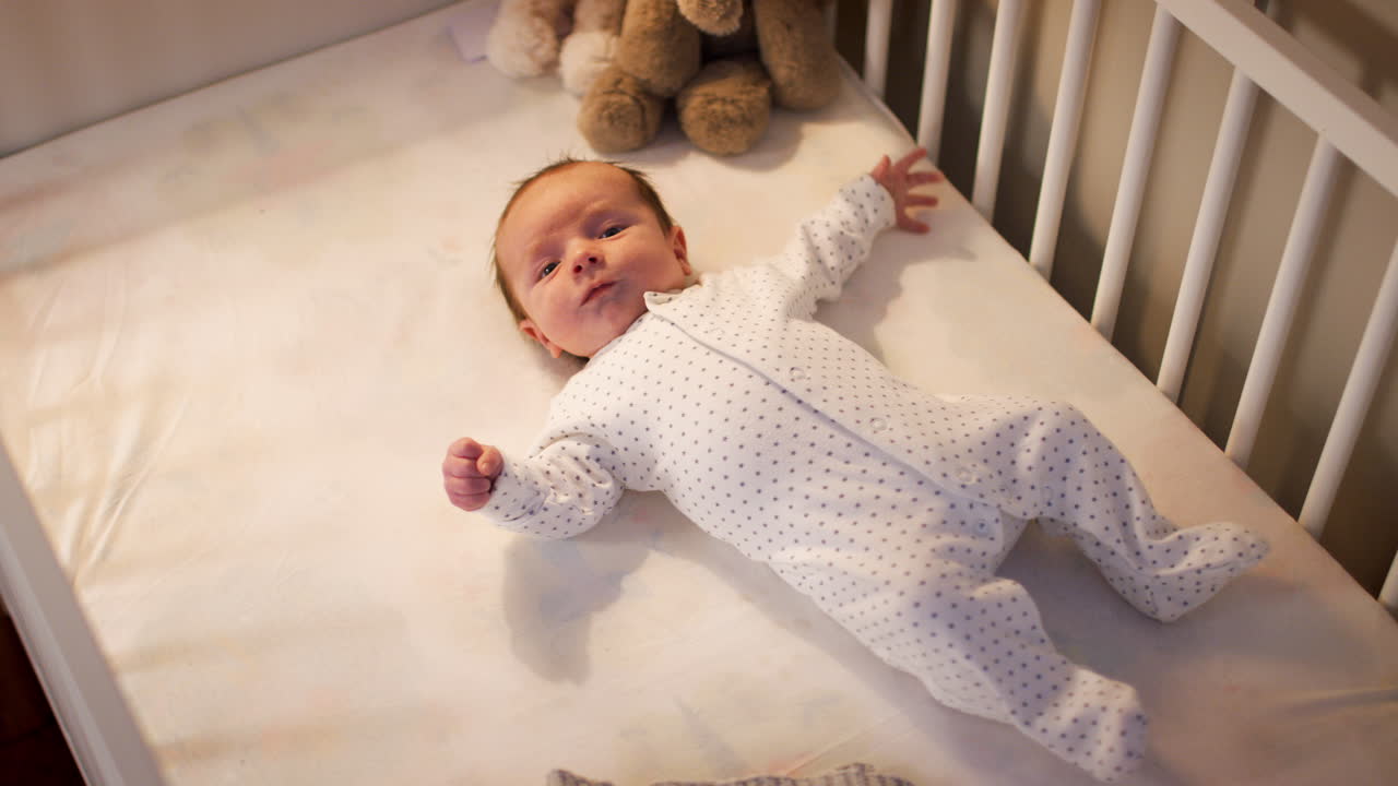 Neonato sdraiato sulla schiena nella culla della cameretta all'ora della nanna.