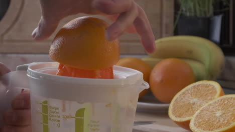 hand squeezing orange juice by a plastic squeezer for refreshment drink in the morning