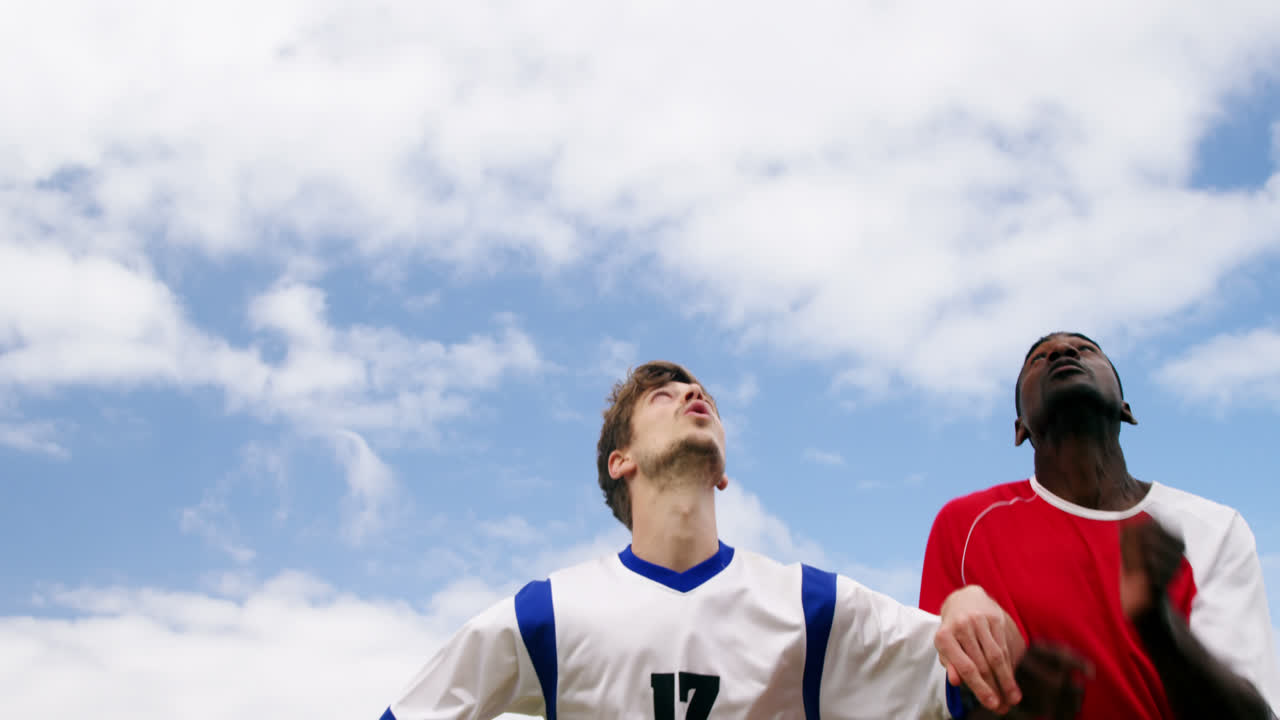 dos jugadores de fútbol saltando para golpear una pelota