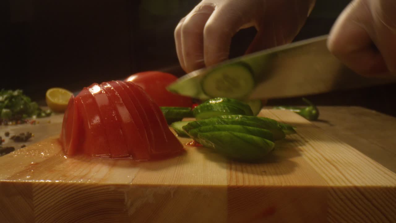 Chef's Hands Slicing Cucumbers and Tomatoes on Wooden Board