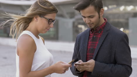 Young-business-people-using-smartphones-on-street