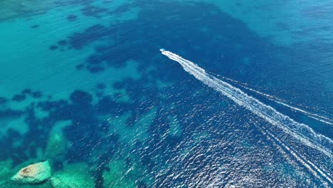 A-boat-cruising-on-the-crystal-clear-ionian-sea-near-corfu-island,-greece,-aerial-view