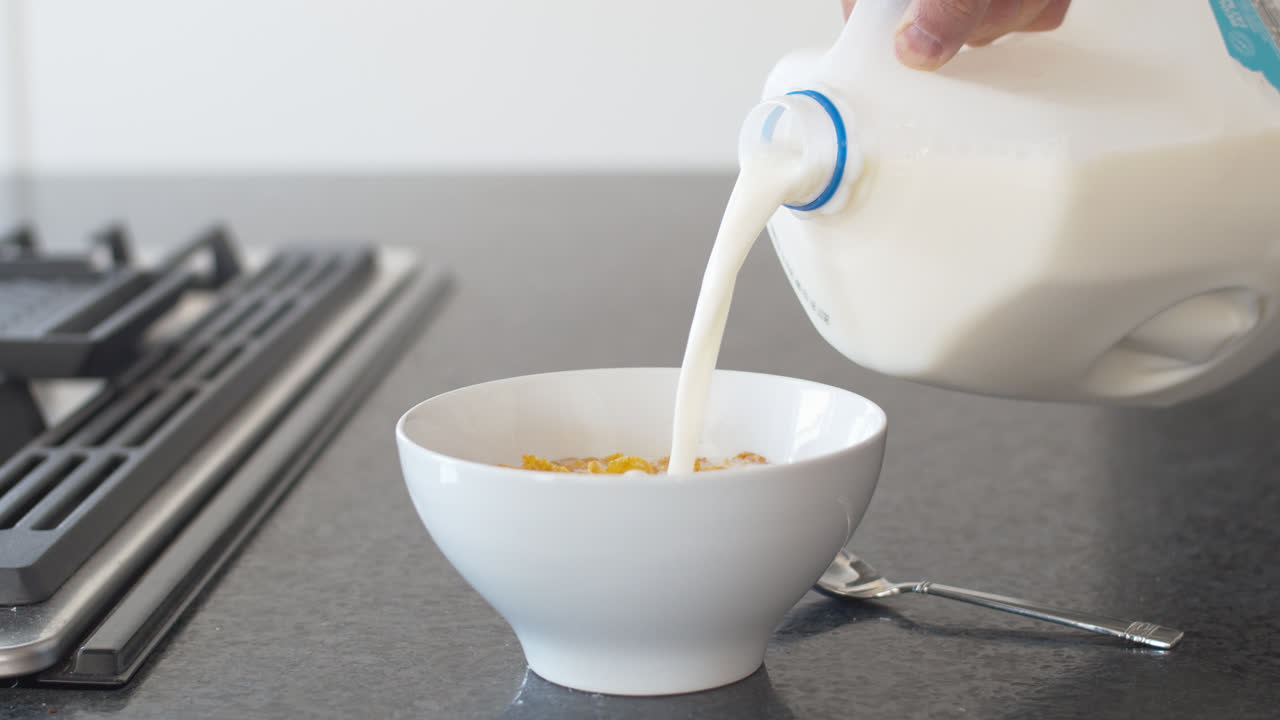 vertiendo leche en un cuenco de cereales