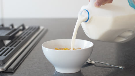 pouring milk into a bowl of cereal