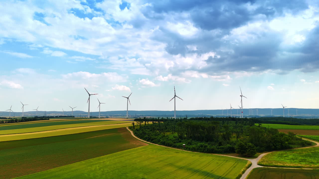 Turbines tower over farmlands. A wide field of wind turbines spins under a cloudy sky, emphasizing sustainable energy in rural areas