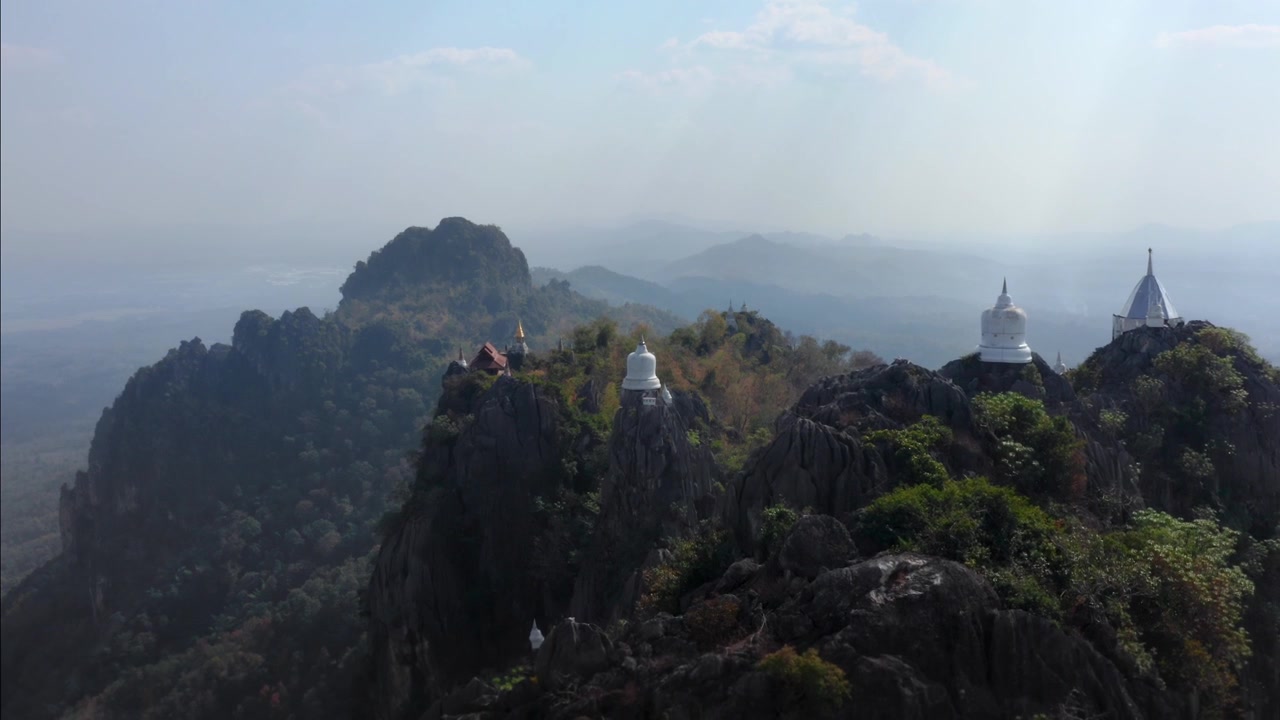 Ripresa aerea con allontanamento che si concentra su belle pagode buddiste bianche sulla cima di alte montagne in Thailandia