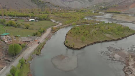 Luftaufnahme-über-Dem-Fluss-Ghizer-Mit-Einem-Geländewagen,-Der-Auf-Einer-Landstraße-Daneben-Geparkt-Ist