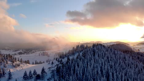 foggy sunset over winter mountains with snow-covered pine trees - aerial drone shot, hyperlapse