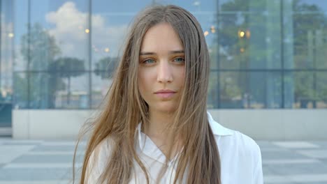 In-front-of-building,-portrait-of-attractive-female-model-posing-with-serious-face-look