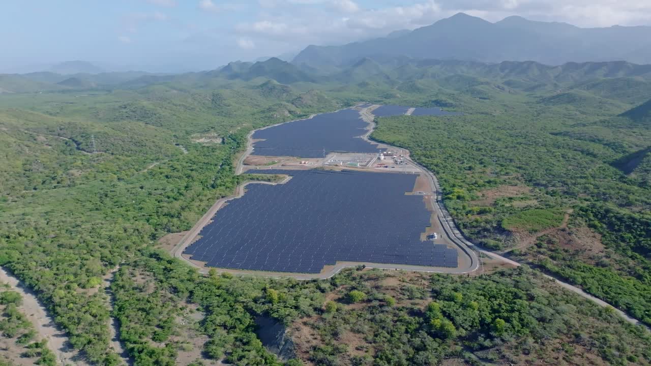 tomada aérea amplia de una granja de paneles solares rodeada por una zona pintoresca de la república dominicana