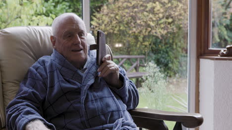 elderly man in robe using cell phone indoors