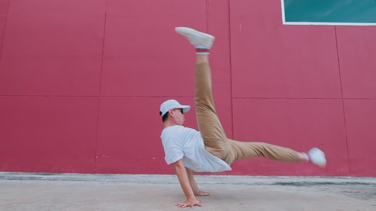 Dancing man performing breakdancing in street wall having fun