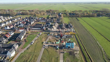 aerial of construction site in a newly built suburban neighborhood surrounded by green meadows - drone flying backwards