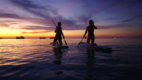 couple paddleboarding at sunset