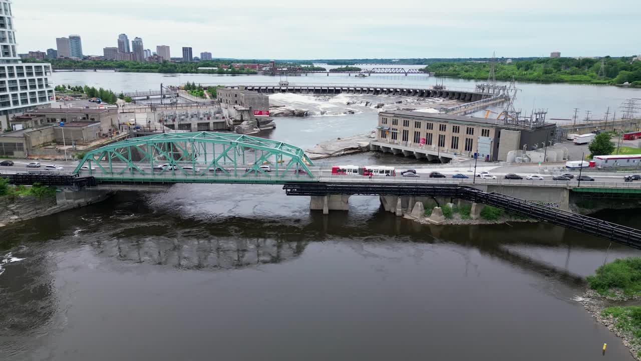 A bridge hydro electric dam and waterfall on an urban river. Tracking aerial shot