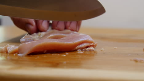 hand cuts raw chicken into strips