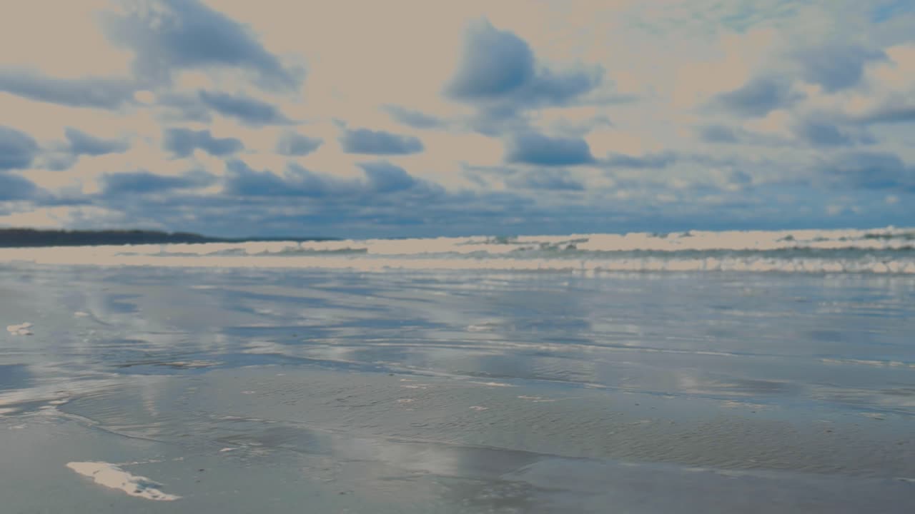 la vista panorámica se mueve desde el mar ondulado a la playa. el mar se arrastra en la playa de arena blanca con árboles. las olas de espuma blanca en la playa. la superficie ondulada del mar refleja un hermoso cielo brillante, un día soleado.