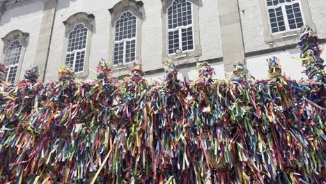 The video starts at the towers of the Church of Bonfim in Salvador, then pans down to reveal a fence full of colorful fitinhas, symbolizing faith, promises, and Afro-Brazilian spirituality.