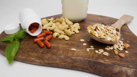 toma de pan de una tabla de cortar con albahaca, pastillas rojas con envoltorio blanco para tabletas y anacardos con cereales-1