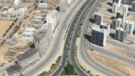 Aerial-drone-tilt-down-shot-over-multi-storied-buildings-close-to-Sindh-Square-Roundabout-in-Bahria-Town,-Karachi,-Pakistan-on-a-bright-sunny-day