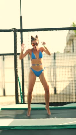 woman jumping on trampoline in bikini