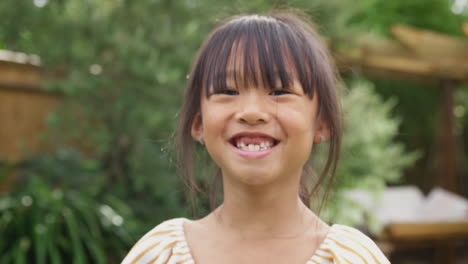 portrait of smiling asian girl with missing front teeth having fun in garden at home