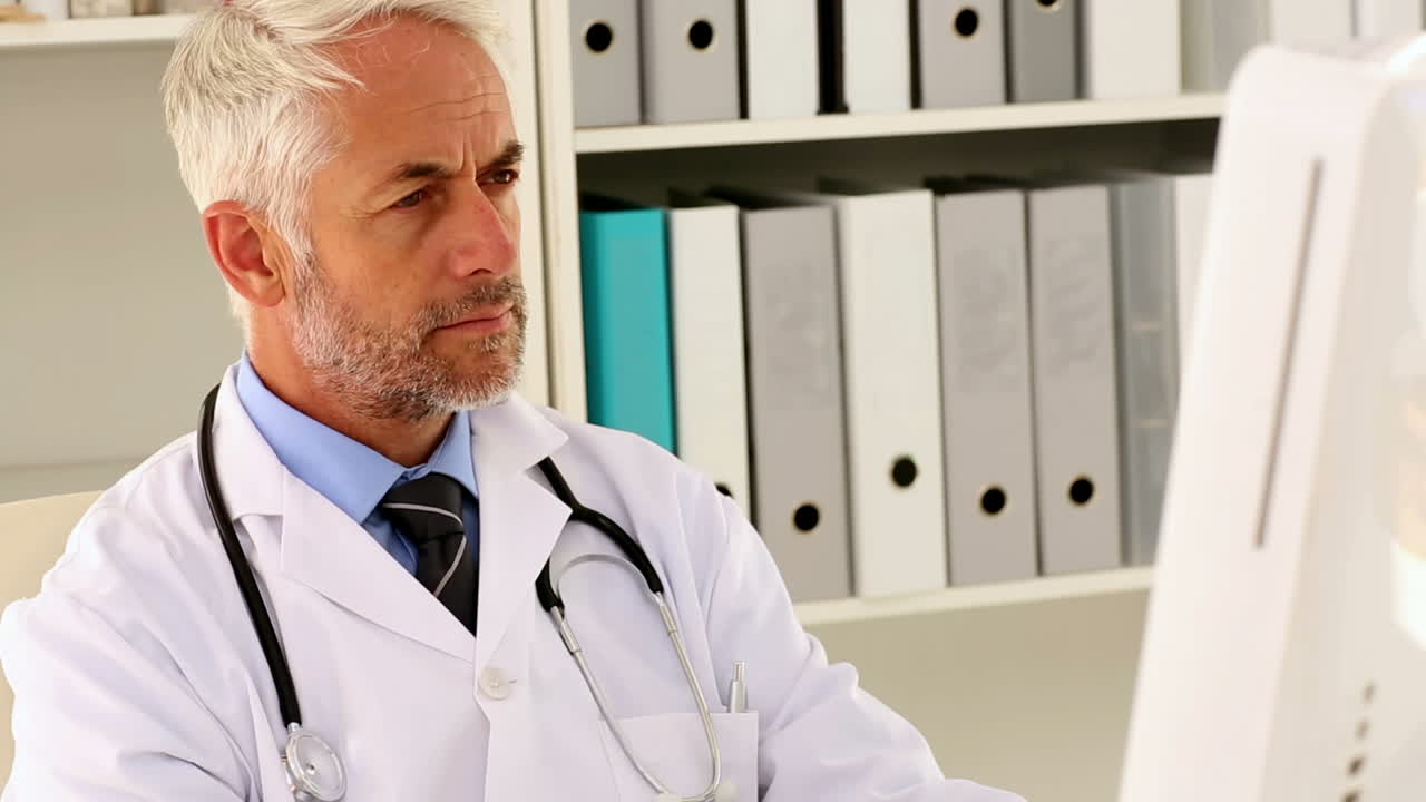 Focused doctor sitting at his desk using his computer