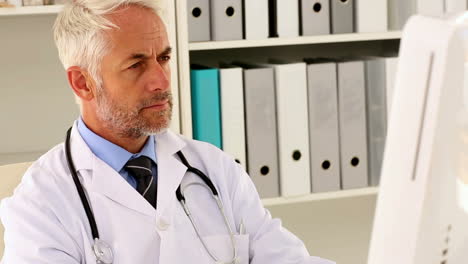 focused doctor sitting at his desk using his computer