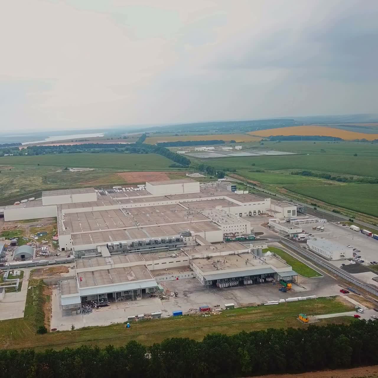 Aerial view of modern industrial building surrounded by green fields. Large modern production plant