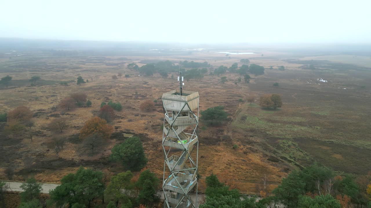 imágenes aéreas que rodean una torre de vigilancia en una reserva natural de brezo, en un frío día de otoño