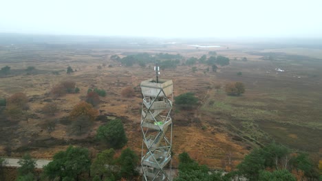 aerial footage circling a watchtower in a heather nature reserve, on a cold autumn day