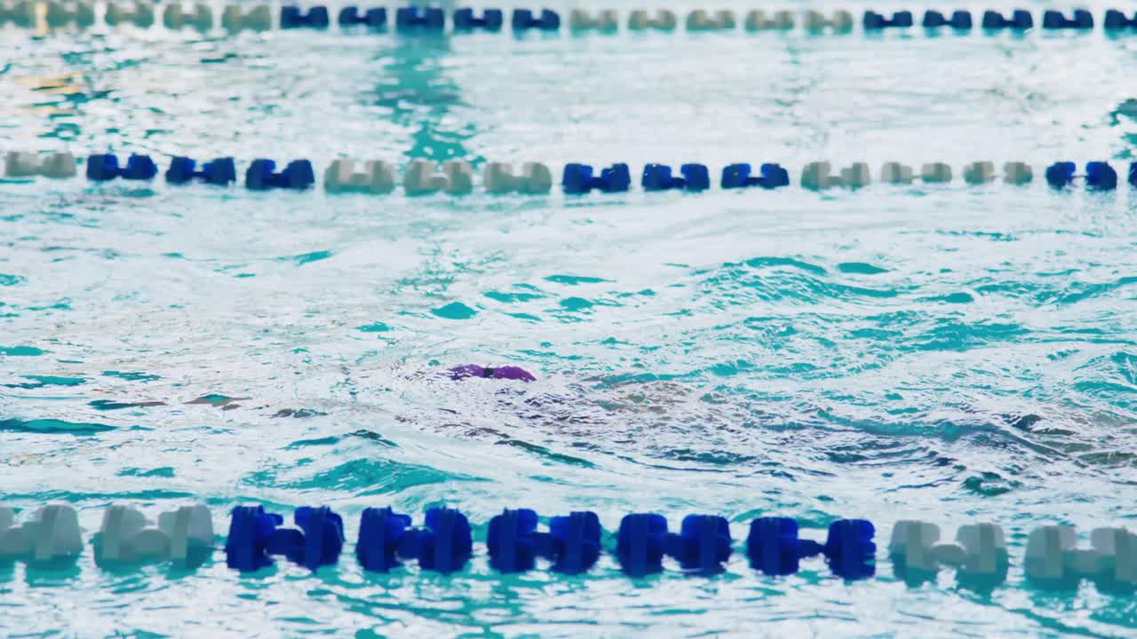Un nadador decidido en movimiento muestra su técnica y perseverancia en una piscina cubierta, destacando la intensidad del entrenamiento acuático y el espíritu competitivo