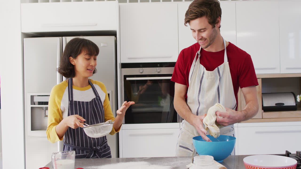 video de una pareja feliz y diversa horneando juntos en la cocina