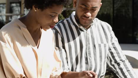 Relaxed-young-couple-looking-at-smartphone-and-talking