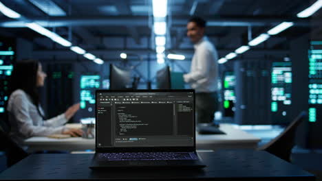 Focus on laptop used by engineers coding in modern data center