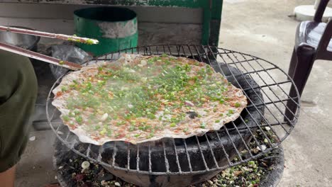 Person-is-grilling-rice-paper,-one-of-the-favorites-in-Asian-cousin,-also-being-called-“pizza-Dalat”,-street-street-food-concept