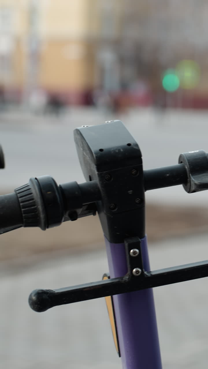 vista cercana de scooters eléctricos púrpuras estacionados en un área urbana bulliciosa, el fondo incluye detalles borrosos de un paisaje urbano con coches en movimiento y personas