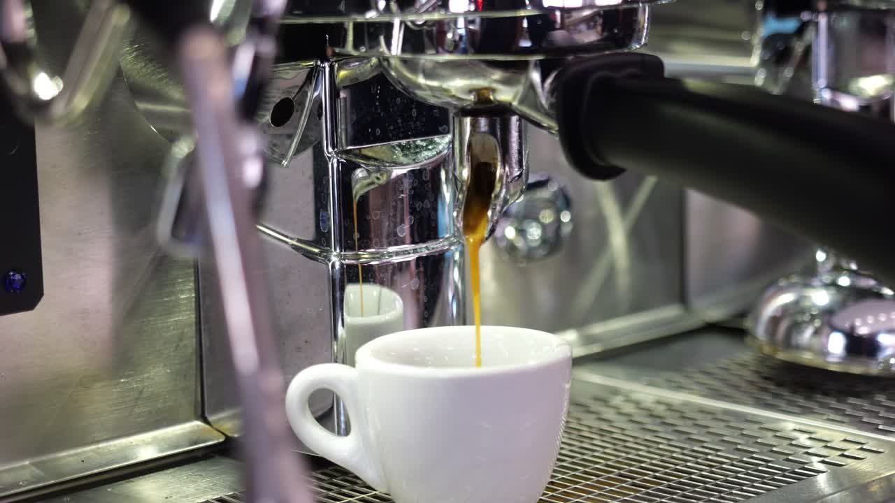 Close-up of rich espresso flowing into a white cup from a stainless steel machine, capturing the moment of preparation in a contemporary café setting