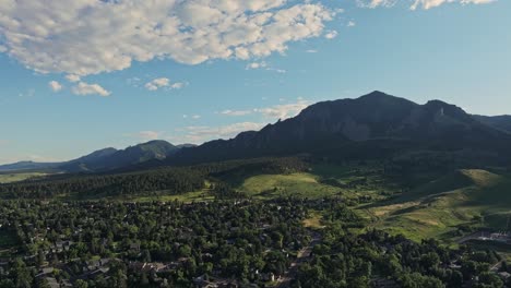 aerial sobre las colinas boscosas de boulder con los picos de las montañas flatirons en el fondo, colorado, ee.uu.