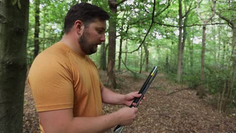 Zeitlupe-Eines-Mannes,-Der-Auf-Einem-Campingplatz-Im-Wald-Zeltstangen-Zusammenbaut