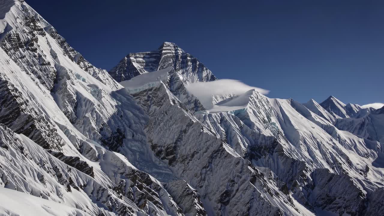 Aerial view of snow-covered mountain peaks under a clear blue sky, capturing the majestic landscape