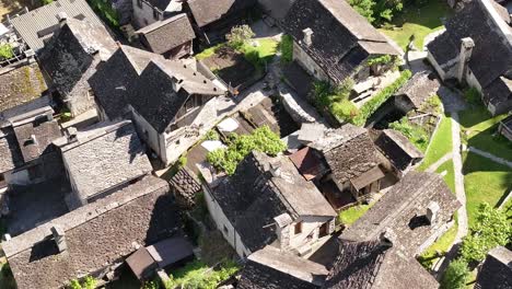 stone houses with slate roofs nestled in greenery near a waterfall, traditional architecture of maggiatal vallemaggia, switzerland