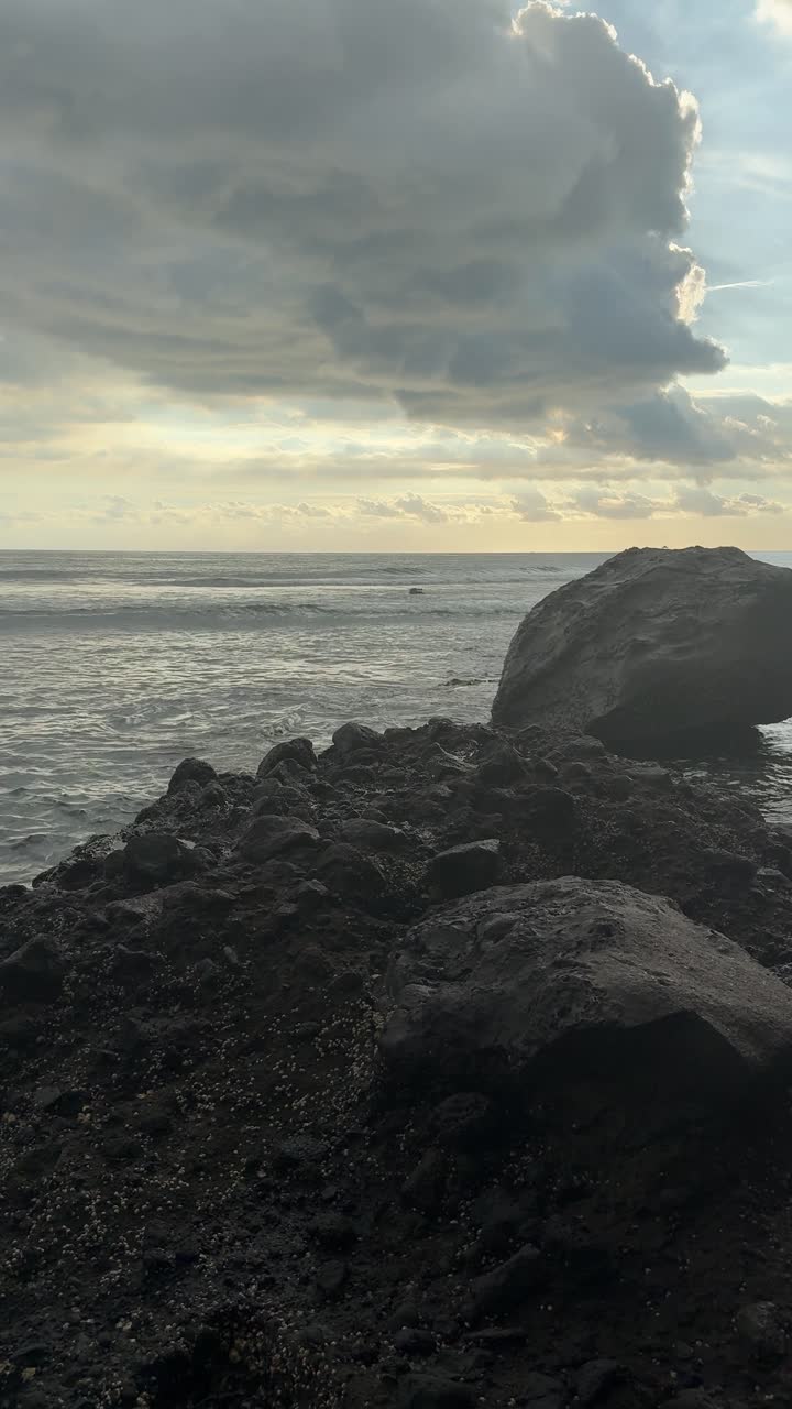 Ocean Waves Crashing on Dark Rocky Coastline Under Cloudy Sky